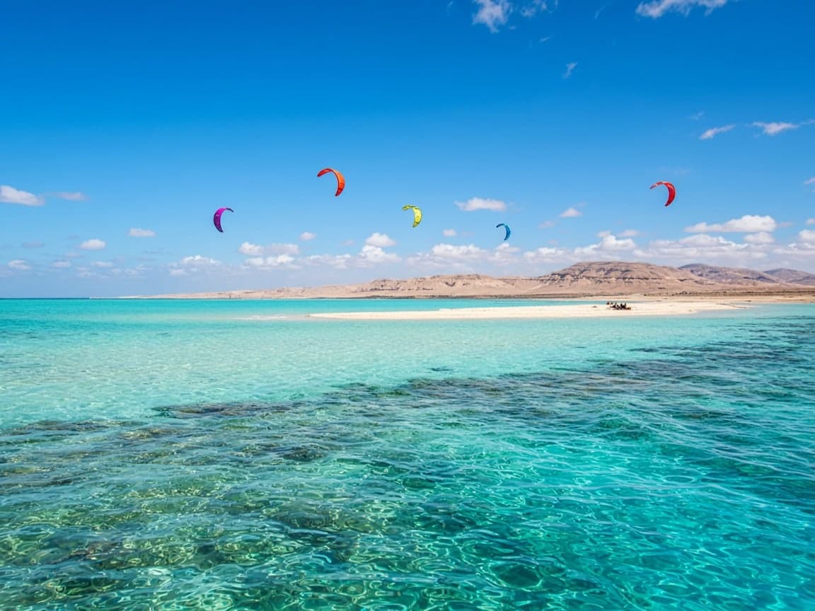 A shallow lagoon with kites in the distance.